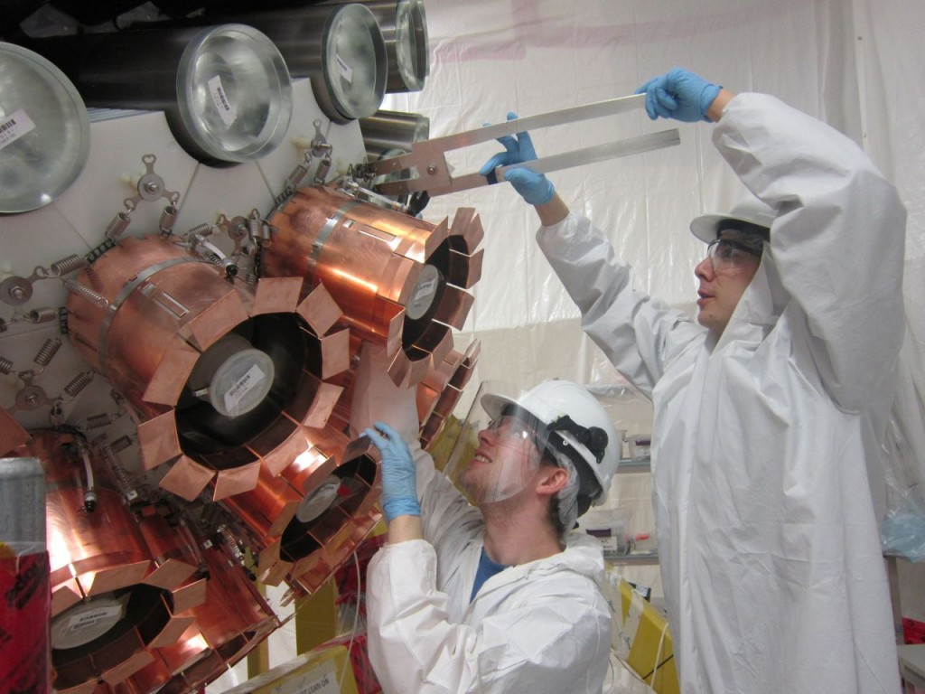 Two science students installing a Photomultiplier Tube mount on the DEAP-3600 detector.