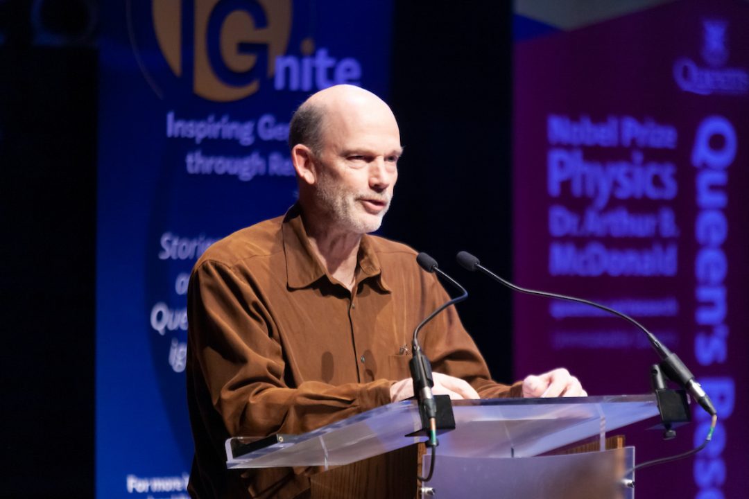 Tony Noble speaks into a microphone while standing at a podium