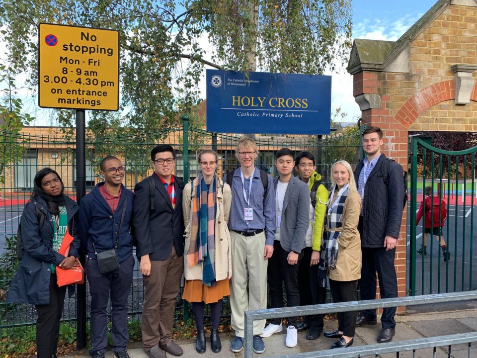 Nine people stand together and pose below a sign reading 