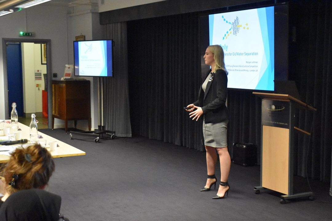 Morgan stands next to a podium and presentation, speaking to an audience