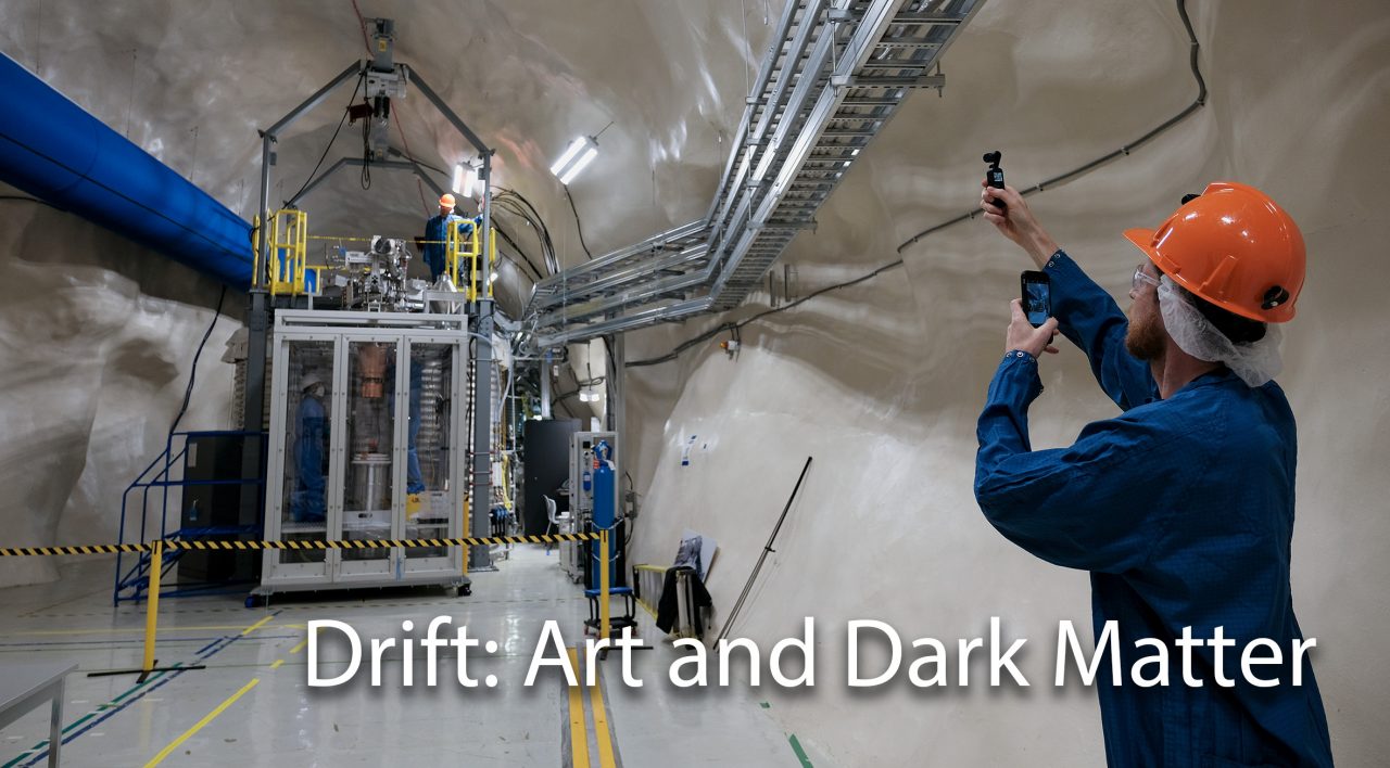 DRIFT: Art and Dark Matter. A background image shows people working in a research facility, wearing personal protective equipment (jumpsuits and hard hats)