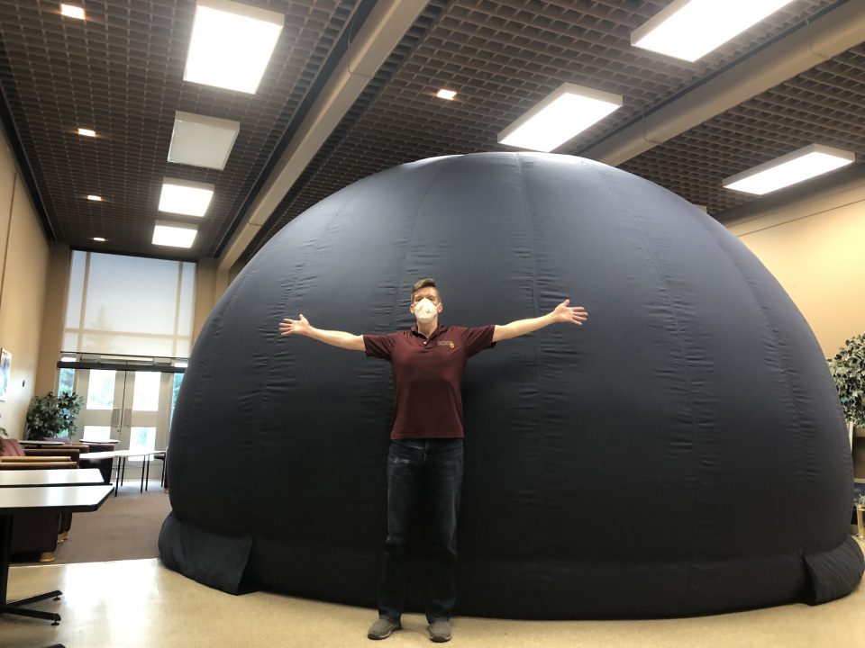 Man stands in front of the inflatable dome, showing its size.